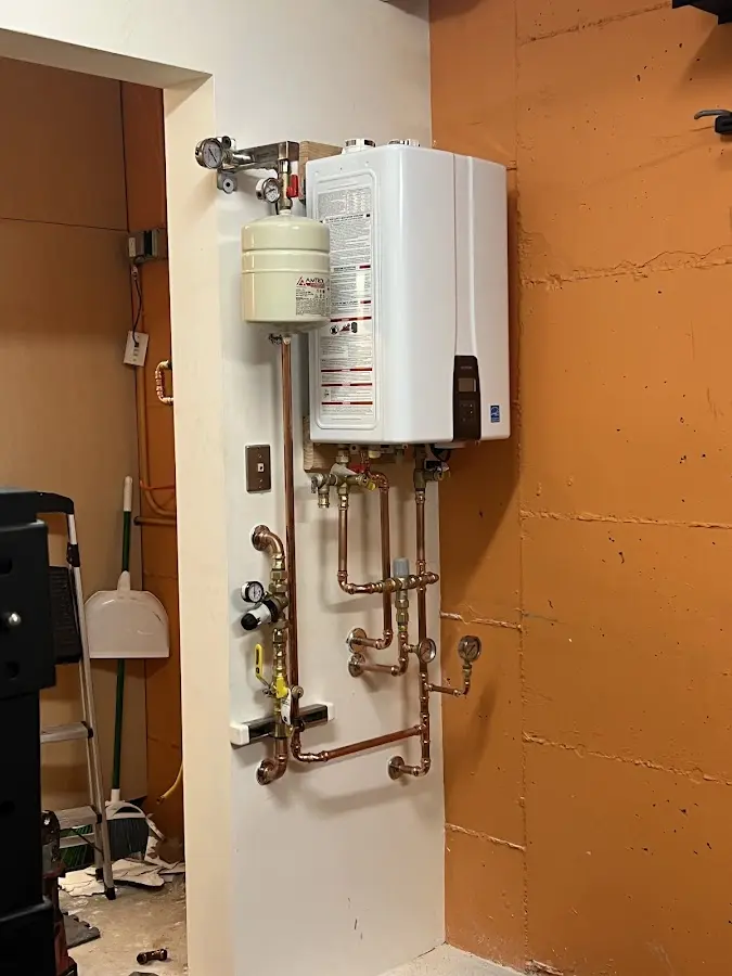 Plumbing technician inspecting water heater connections in Bensley